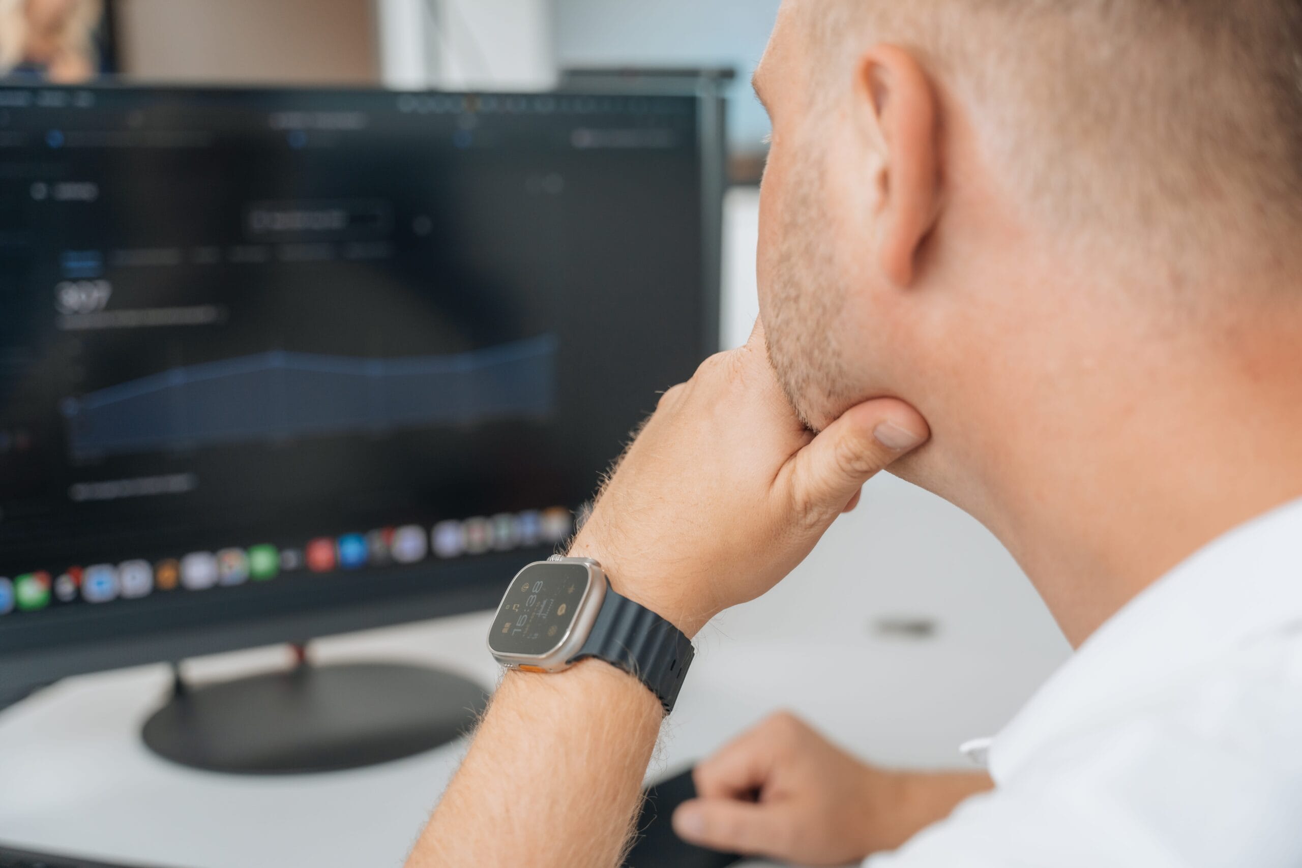 Alexander Reith blickt auf ein Performance-Dashboard auf dem Monitor, Apple Watch Ultra sichtbar am Handgelenk