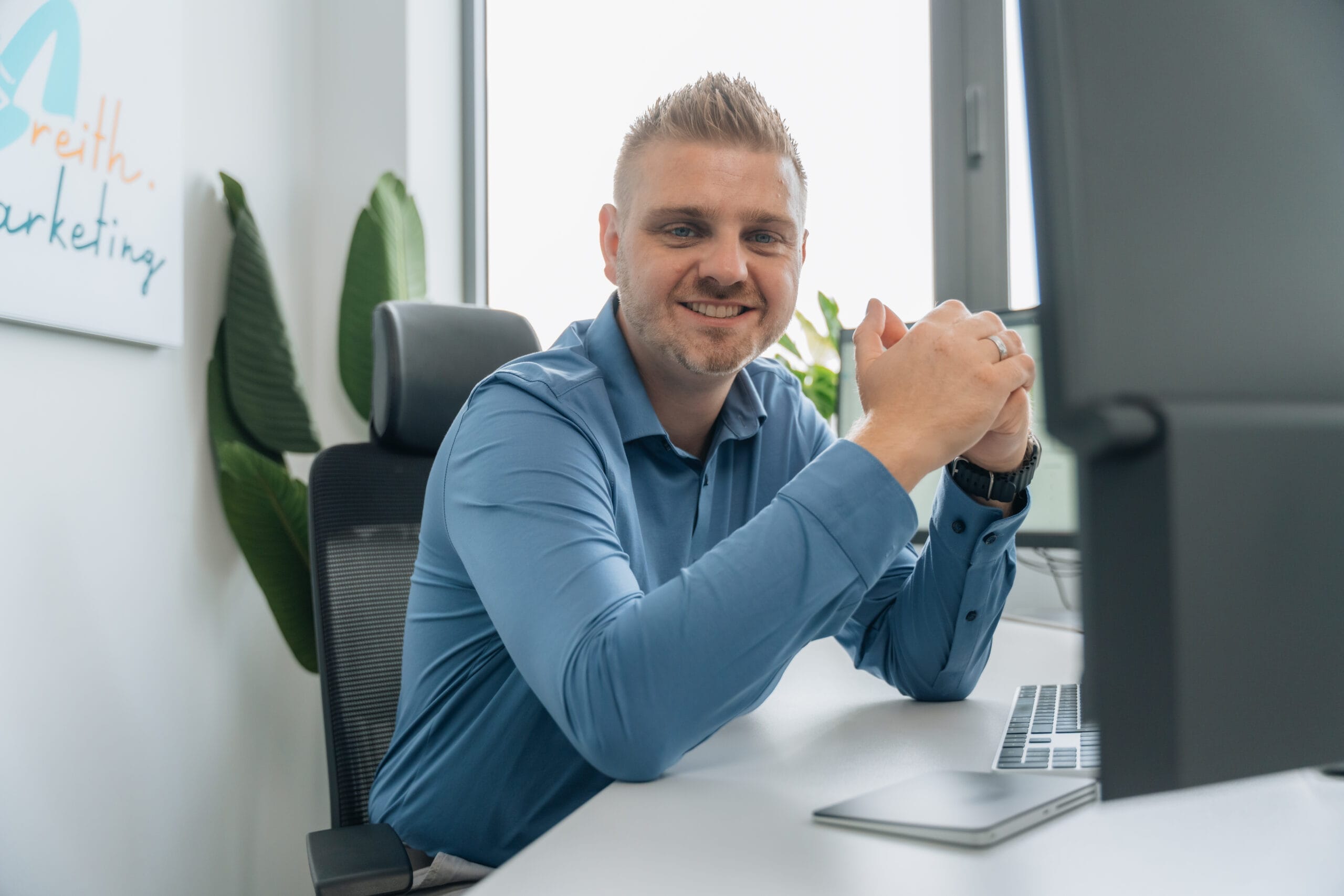 Alexander Reith blickt am Schreibtisch in die Kamera.