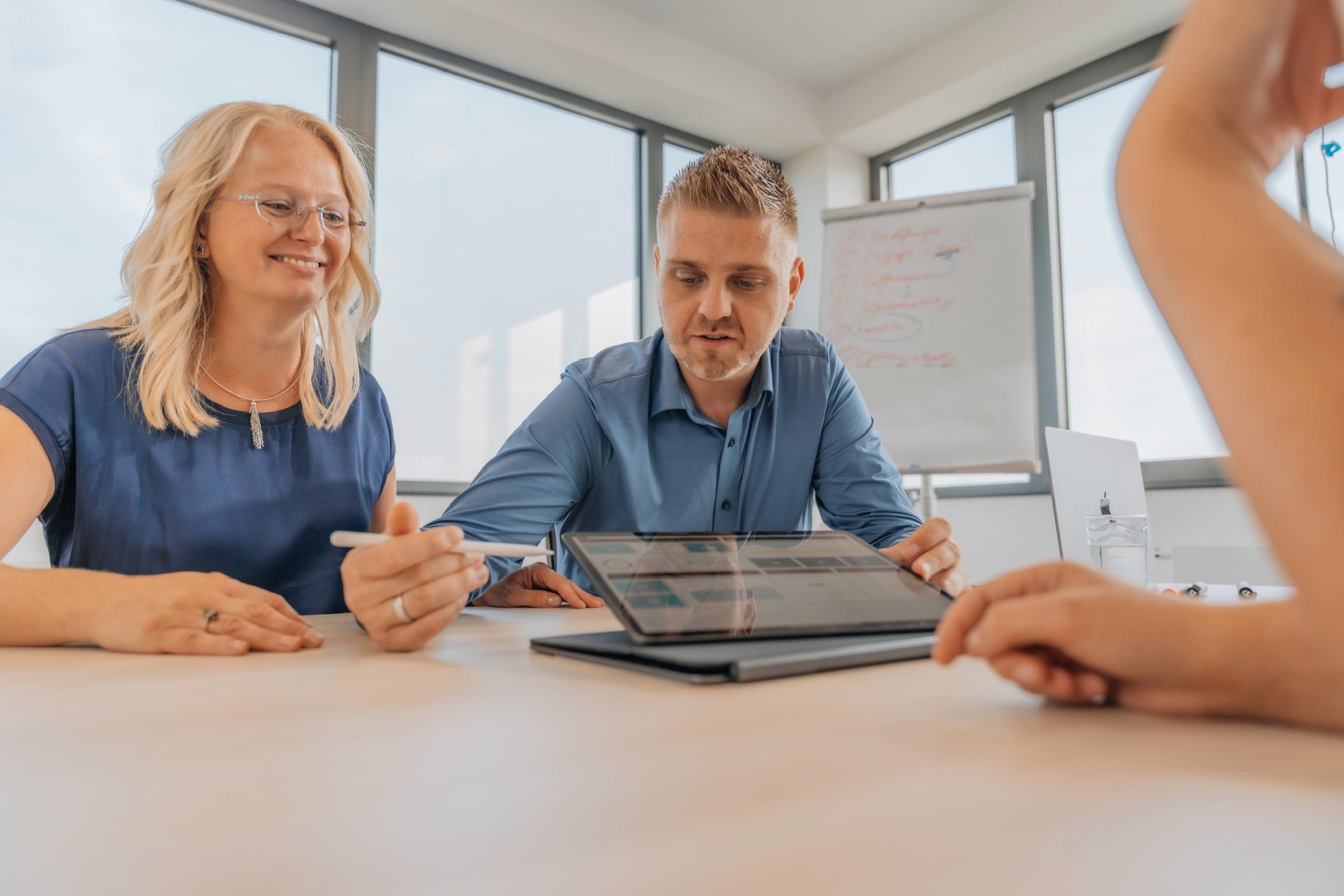 Alexander und Justine Reith präsentieren einer Kundin Inhalte auf dem iPad im Besprechungsraum von reith.marketing
