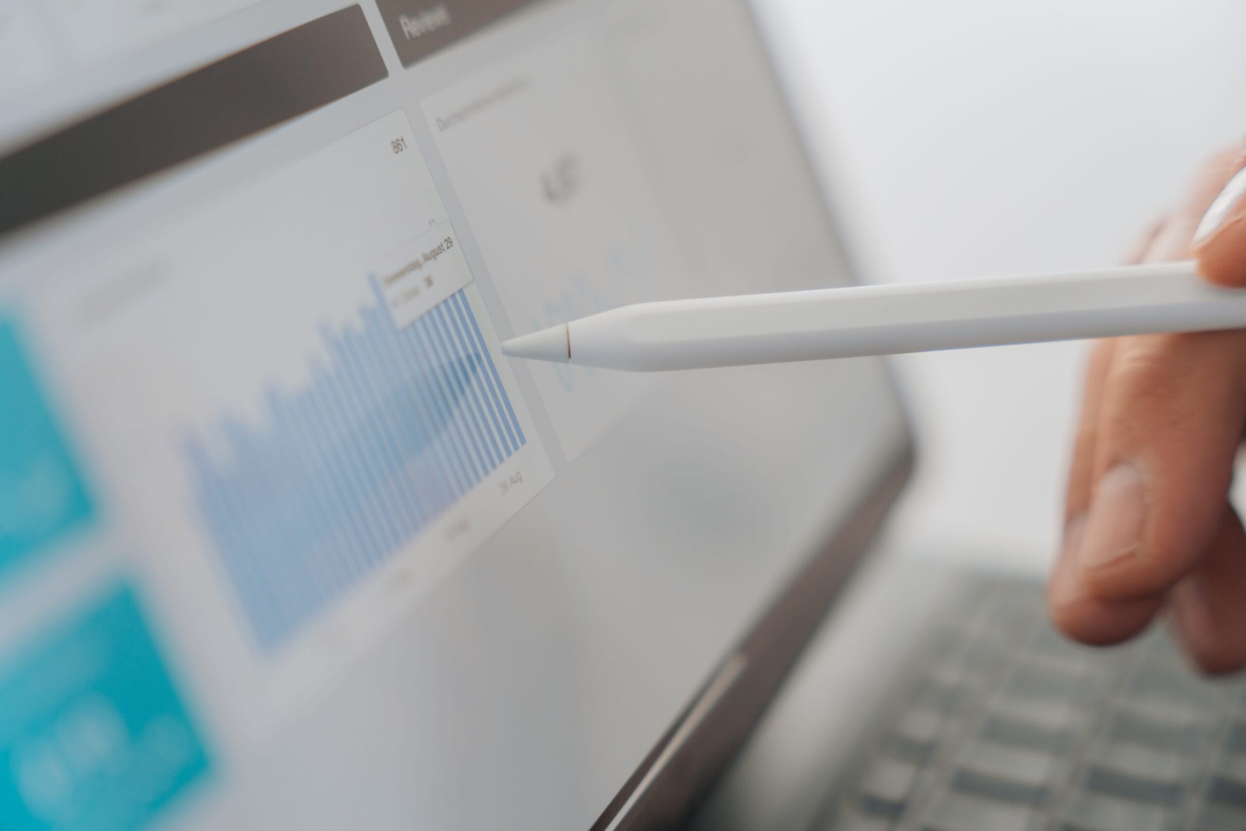 Apple Pencil zeigt auf KPI-Dashboard mit blauer Balkengrafik auf einem Monitor, Symbolbild für datengetriebenes Marketing bei reith.marketing